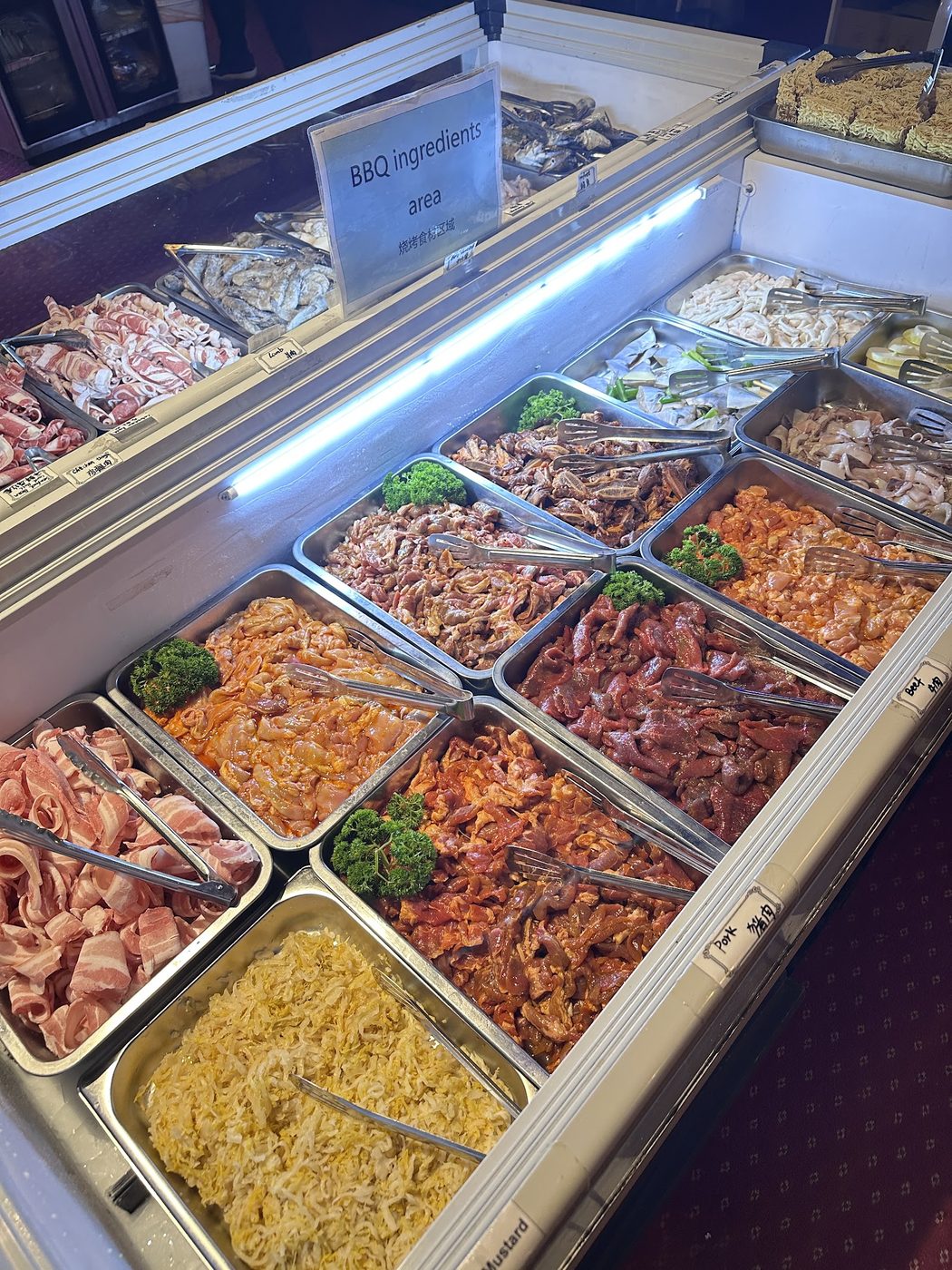 Barbecue counter with trays of sliced lamb, pork, beef and chicken